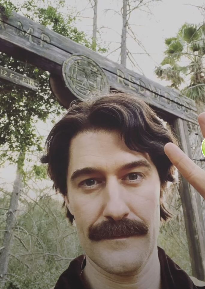 a man with a fake mustache and moustache holding up a green frisbee