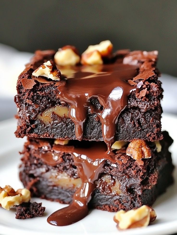 three pieces of chocolate cake on a white plate with walnuts and drizzle