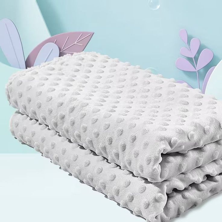 two blankets are stacked on top of each other in front of a butterfly wallpaper