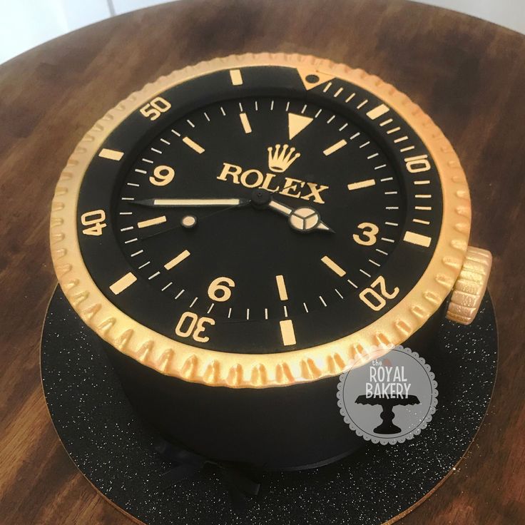 a black and gold rolex watch sitting on top of a wooden table