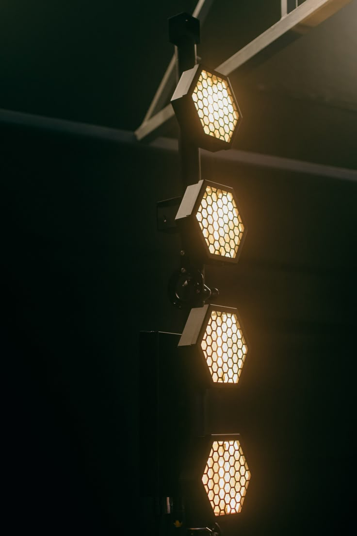 three street lights are lit up in the dark with light shining on them and hexagonal shapes