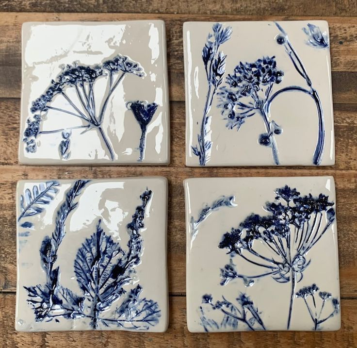 four blue and white plates with flowers on them sitting on a wooden table, top view