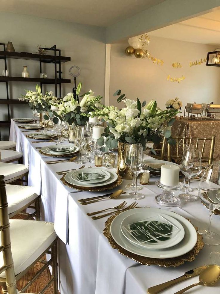 the table is set with white and gold place settings