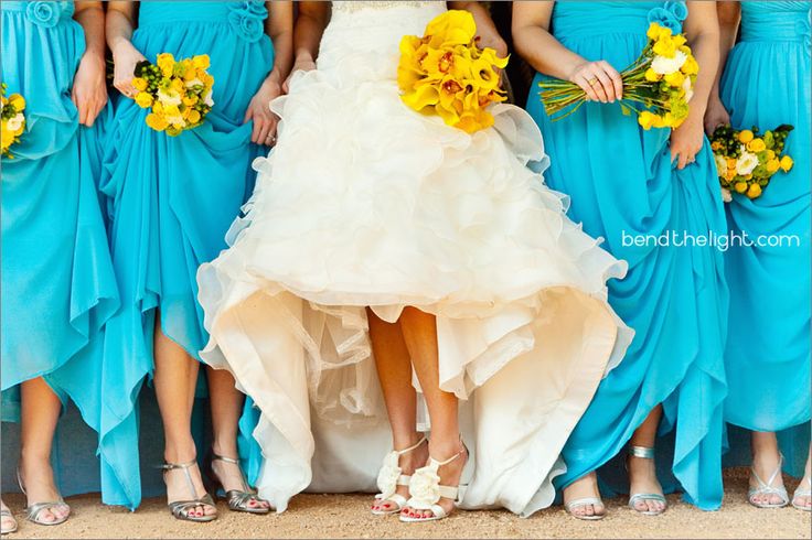 a group of bridesmaids in blue dresses with yellow flowers