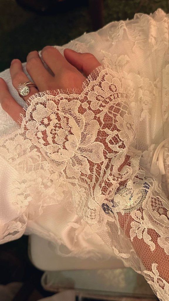 a woman wearing a wedding dress and holding onto her lace covered arm with the ring