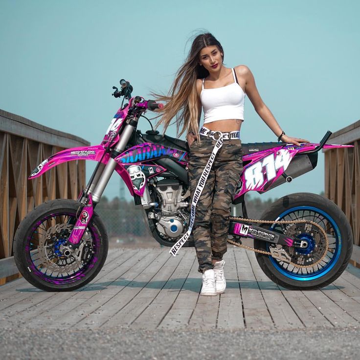 a woman standing next to a pink dirt bike