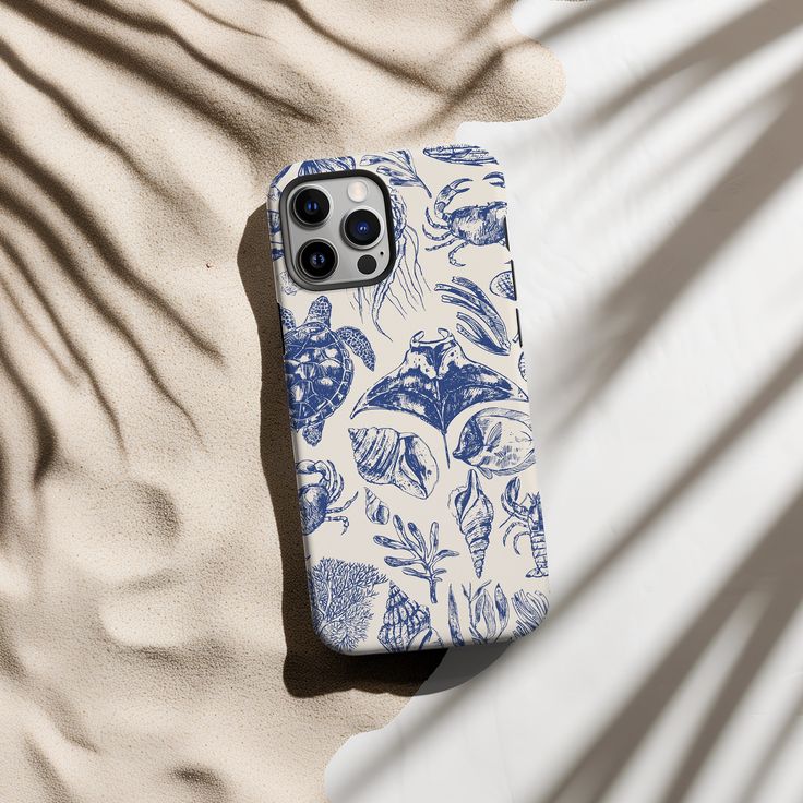 a blue and white phone case sitting on top of sand