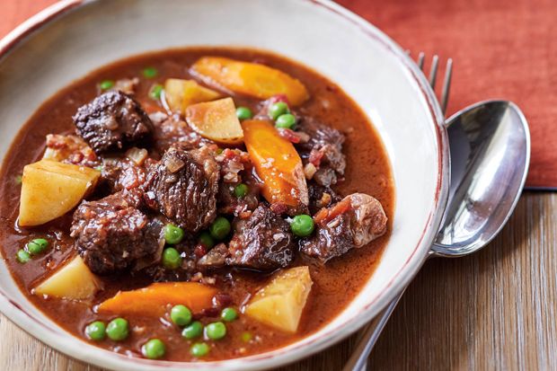 a white bowl filled with stew and peas