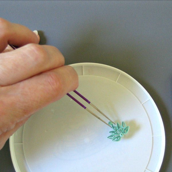 a person is holding an object in front of a plate with two sticks sticking out of it