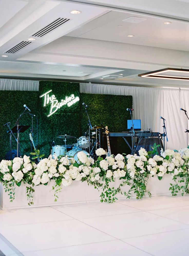 the stage is decorated with white flowers and greenery