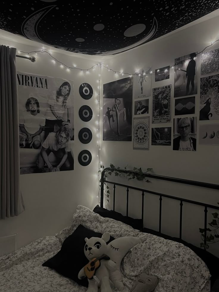 a bedroom decorated in black and white with pictures on the wall, lights strung from the ceiling