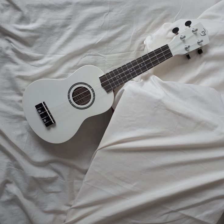 an ukulele laying on a white sheet