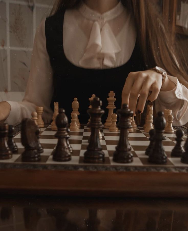 a woman is playing chess on a table