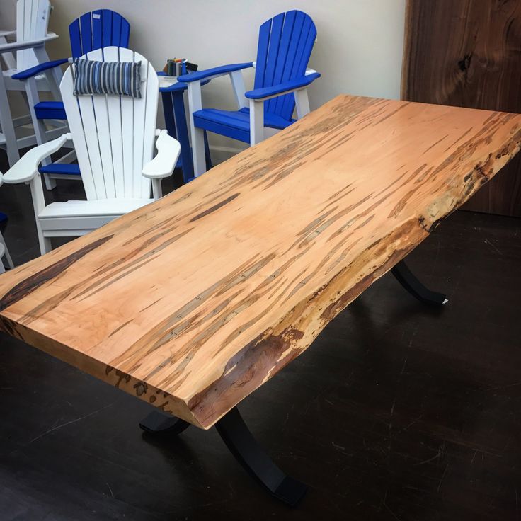 a wooden table sitting on top of a hard wood floor next to blue plastic chairs