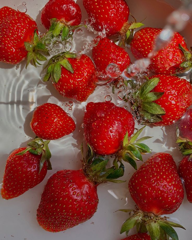 a bunch of strawberries are in a bowl of water