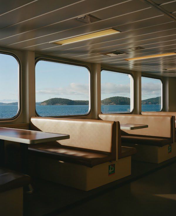 the inside of a boat with tables and benches on both sides looking out at the water