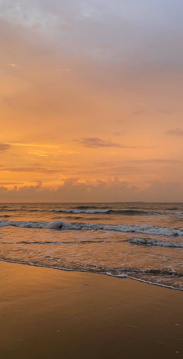 two surfers walking into the ocean at sunset