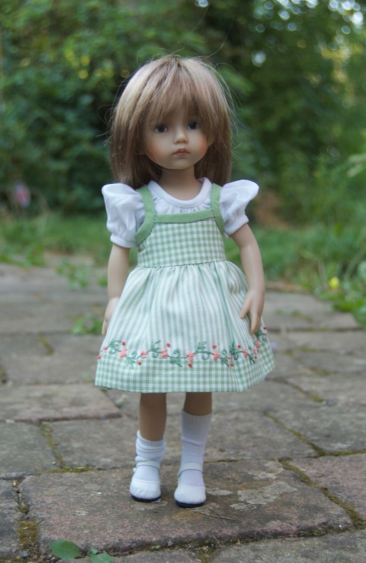 the doll is wearing a green dress and white socks