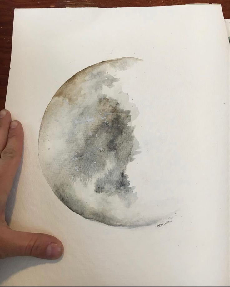 a person is holding up a piece of paper with watercolor paint on it that has a half moon in the middle