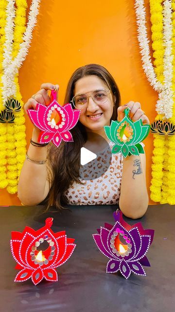 a woman sitting at a table with three paper flowers in front of her and the words happy diwali written on it