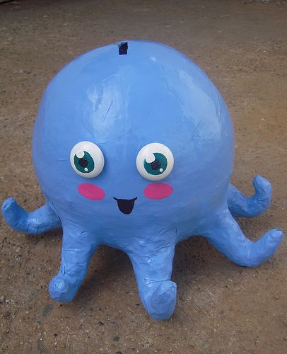 an inflatable blue octopus with big eyes and pink cheeks sitting on the ground