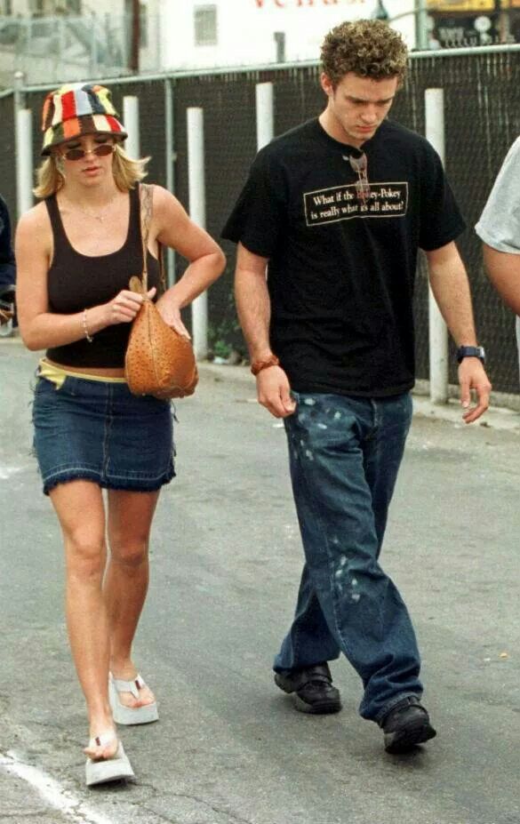 a man and woman walking down the street with one carrying a handbag in her other hand