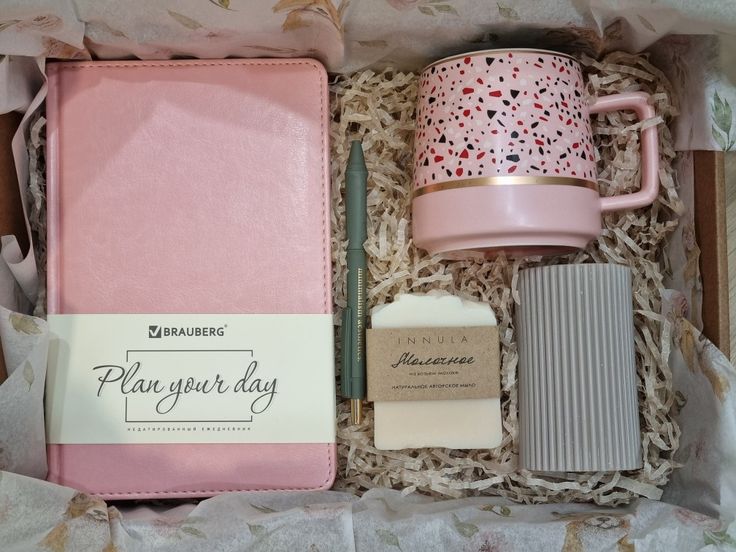 a pink box containing a coffee mug, notebook and other items that are in it