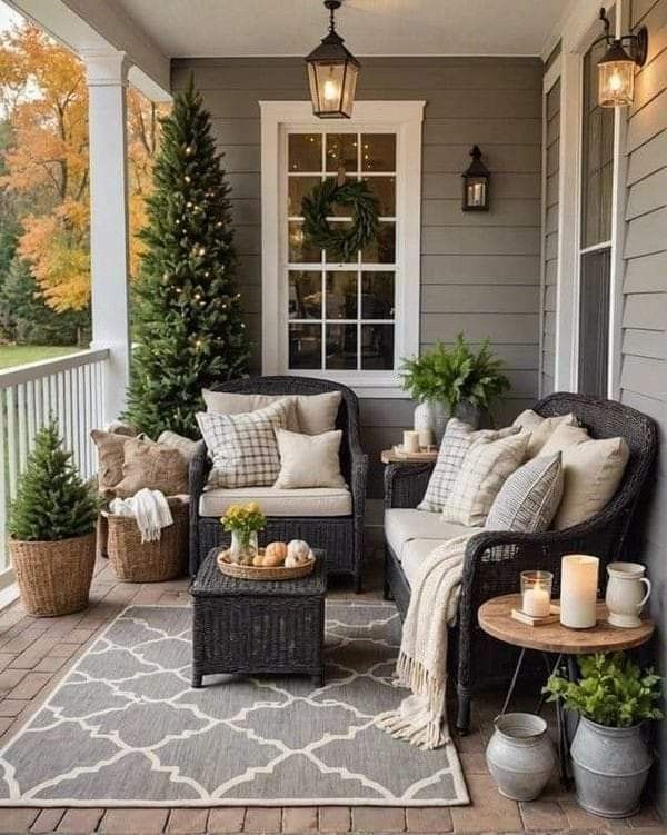 the front porch is decorated with wicker furniture and potted plants on the table