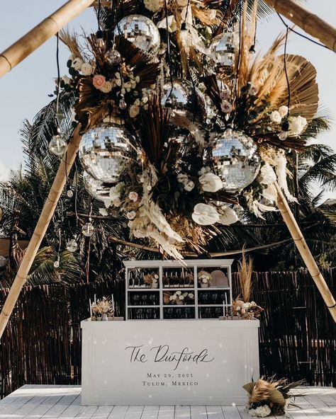 an outdoor ceremony setup with mirrored balls and flowers on the ceiling, surrounded by palm trees