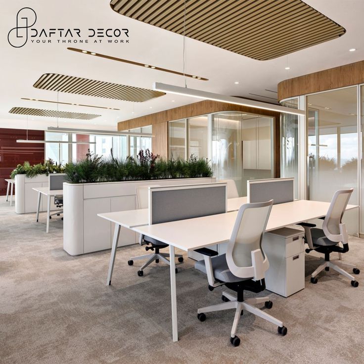 an office with white desks and plants in the middle