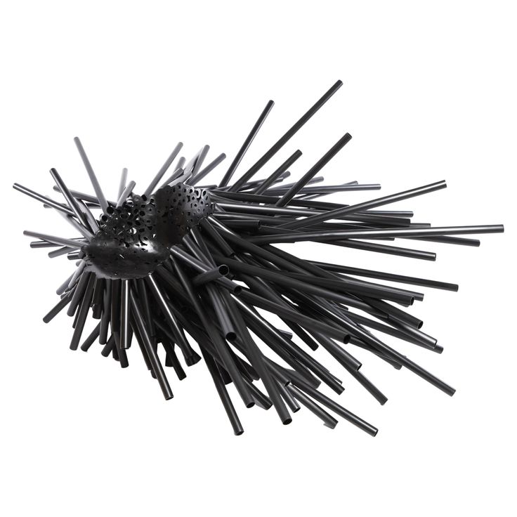 a close up of a black object on a white surface with lots of sticks sticking out of it