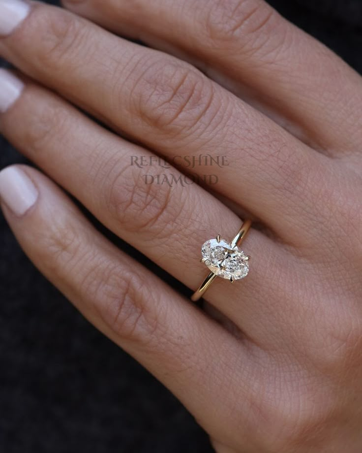 a woman's hand with a diamond ring on top of her finger and an engagement band