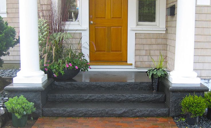 a front porch with potted plants on the steps