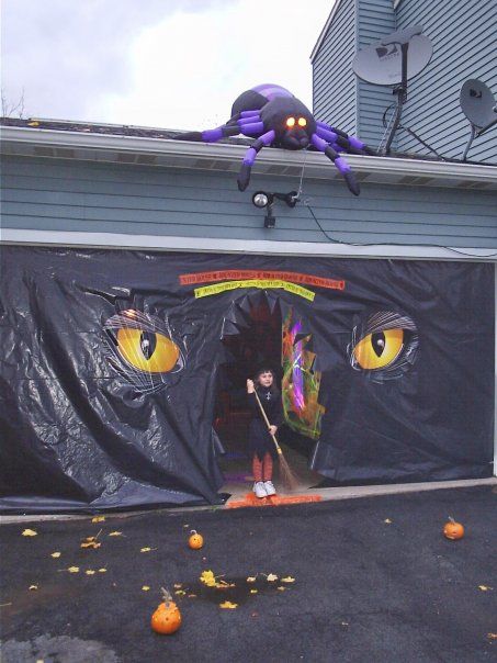 an inflatable spider is on top of a garage door with halloween decorations around it