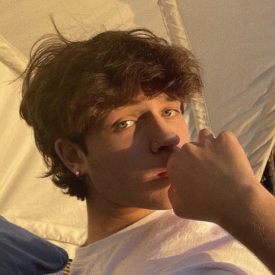 a young man sitting in a hammock with his hand on his chin and looking at the camera