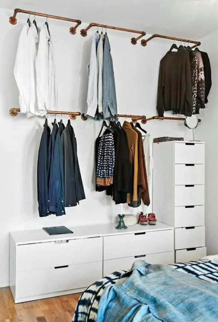 an organized bedroom with clothes hanging on the wall