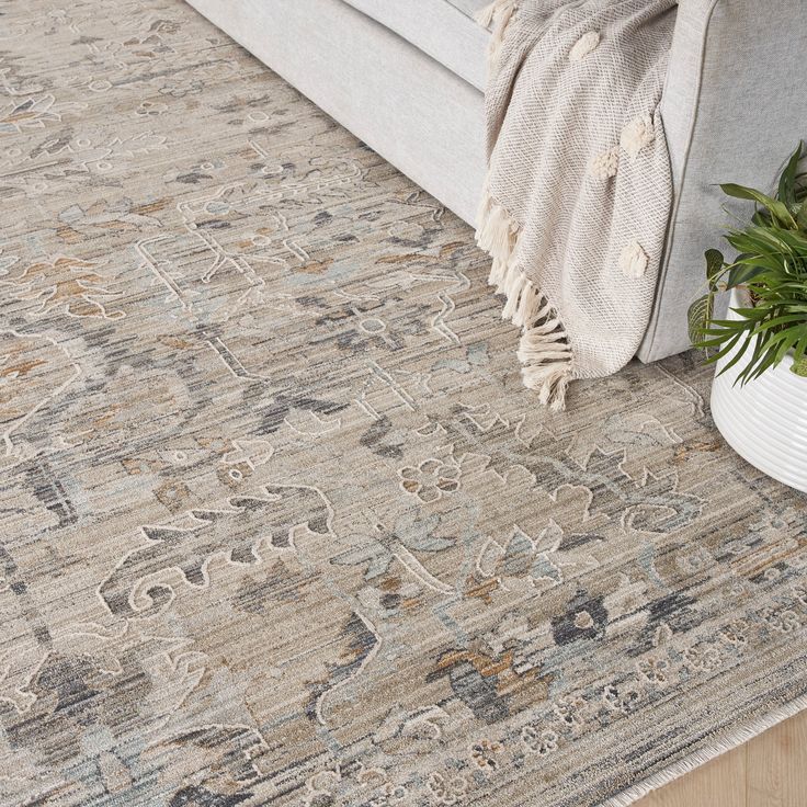 a large rug with an ornate design on the floor next to a couch and potted plant