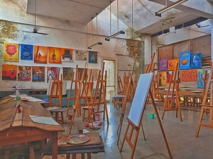 an artist's studio filled with lots of easels and paintings on the walls