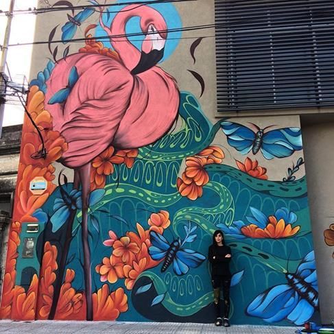 a woman standing in front of a colorful mural