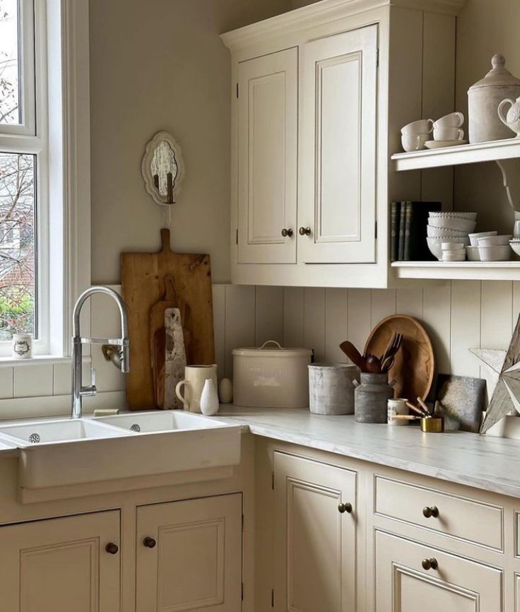 a kitchen filled with lots of white cupboards and counter top next to a window