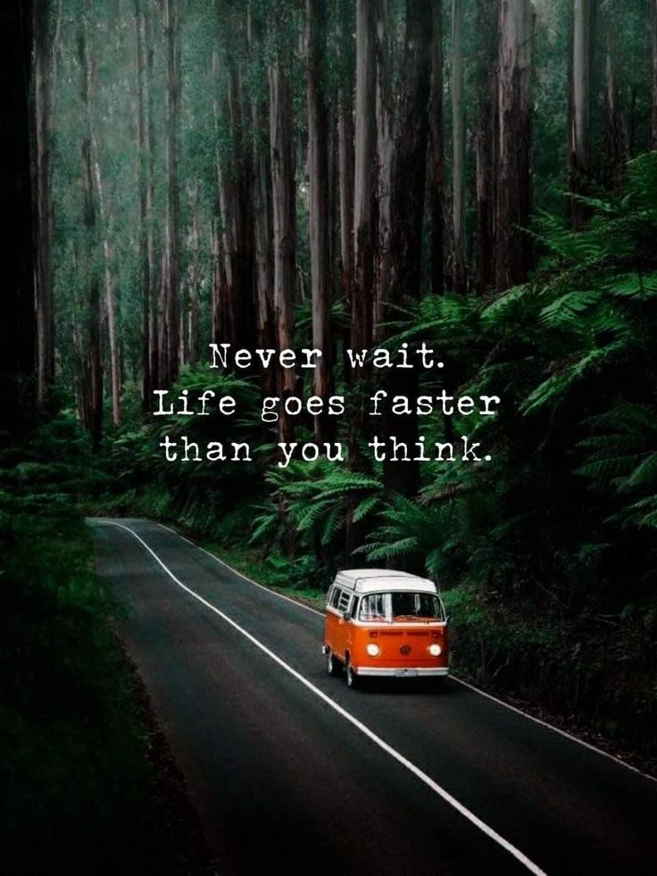 an orange and white van driving down a road in the woods with a quote on it