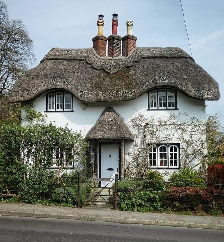 a white thatched roof house with three chimneys