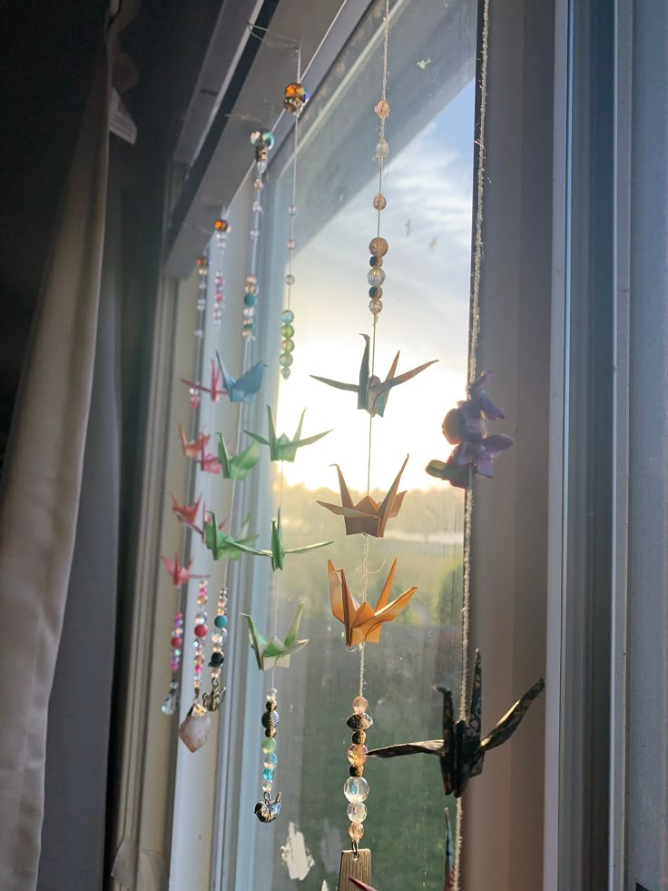 the birds are hanging on the window sill by the curtain rod, which is decorated with beads and glass beads