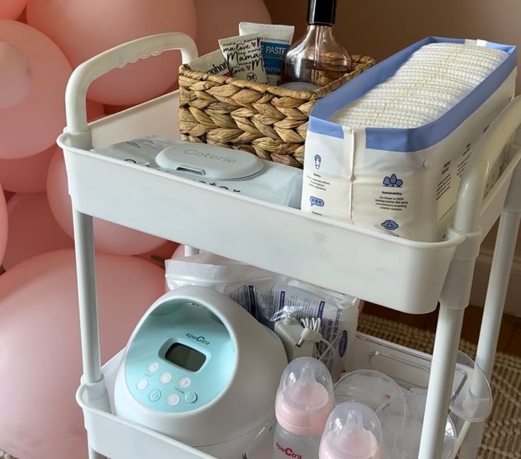 a baby changing table with bottles and diapers on it, in front of balloons