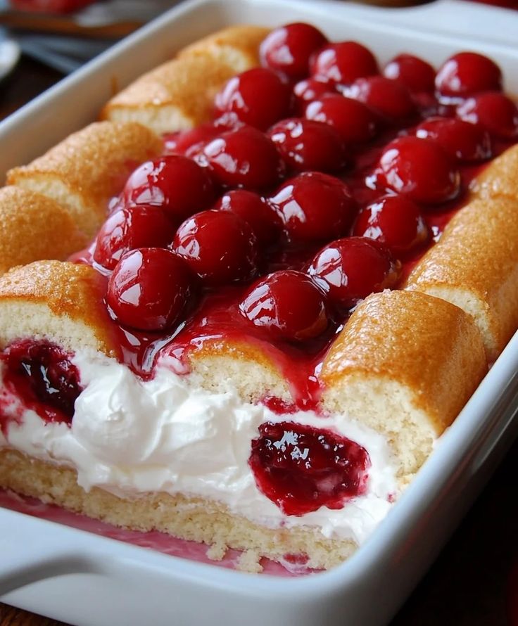 a cake with cherries and whipped cream in a white dish