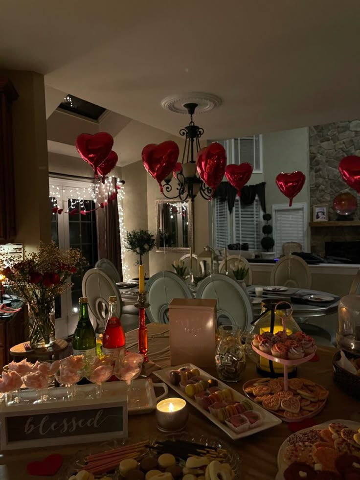 a table filled with lots of food and balloons in the shape of heart shaped balloons