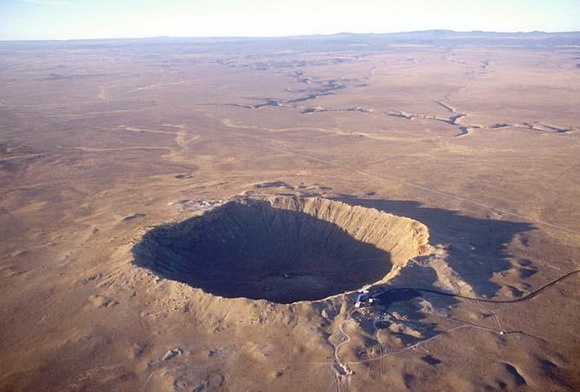 an aerial view of a large crater in the middle of nowhere, surrounded by barren land