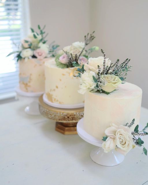 three wedding cakes with flowers on them sitting on a table