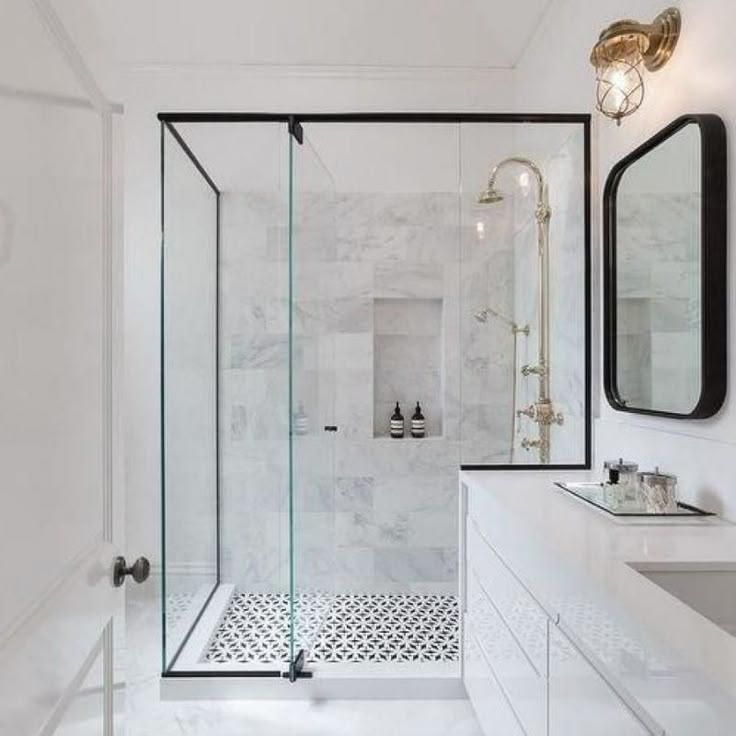 a white bathroom with black and white tile on the floor, shower head, sink, and mirror