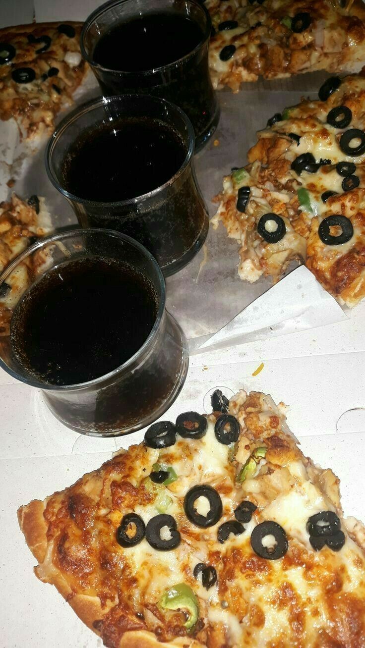 several slices of pizza with olives and cheese on them next to two cups of sauce